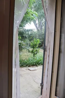 an open door with a view of a garden through a window at Villa MAGRI 3 bedrooms in Cuxac-dʼAude
