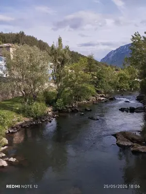 a river with rocks and trees and a mountain at Petit Soleil in Quillan