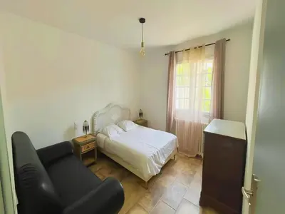 a bedroom with a bed and a chair and a window at Villa in St Denis with Pool & Pyrenees View in Saint-Denis