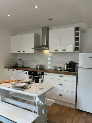 a kitchen with white cabinets and a table with glasses on it at Maisonnette Proche Gare & Centre l Jardin l Clim in Castres