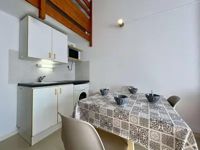 a dining room with a table with chairs and a kitchen at Proche plage du Grazel, Pavillon avec piscine - GN530-008 in Gruissan
