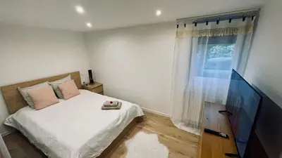 a bedroom with a bed and a flat screen tv at LE HAVRE D'ATHENA - Grand appart, jardin privé, abri vélos & accès rapide A61 in Castelnaudary