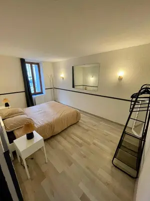 a bedroom with a large bed and a wooden floor at Parenthèse à Deux - T2 Cosy & Calme - Patio - Terrasse - Climatisé - Proche de la cité médiévale in Carcassonne