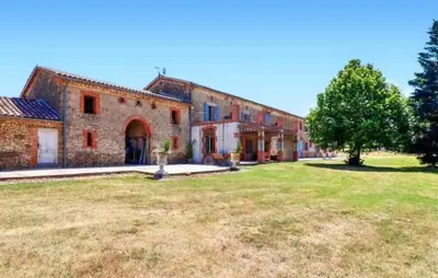 a large brick building with a grass field in front of it at Authentique Maison Campagne in Montredon-Labessonnié
