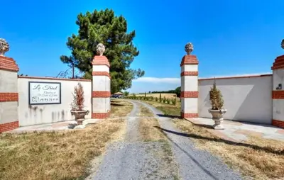 a road leading to a house with two pillars at Authentique Maison Campagne in Montredon-Labessonnié