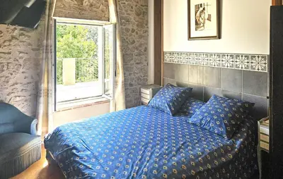 a bedroom with a blue bed with a window at Authentique Maison Campagne in Montredon-Labessonnié