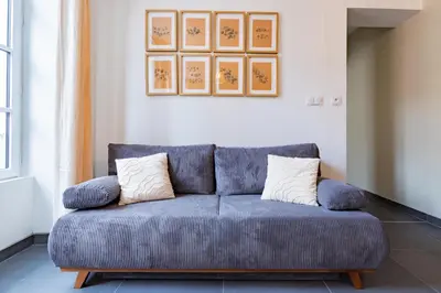 a blue couch in a living room with two pillows at Plein centre - climatisé - à proximité cité médiévale in Carcassonne