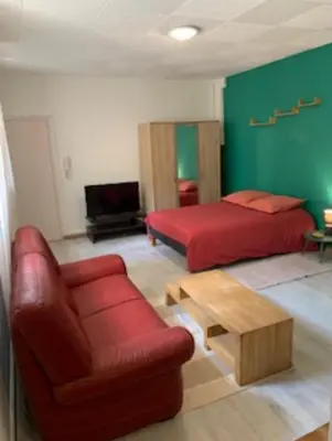 a bedroom with a red bed and a red couch at Carcassonne Studio in Carcassonne