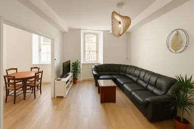 a living room with a black leather couch and a table at Appartement rénové avec 2 chambres et espace bien-être Lavelanet in Lavelanet
