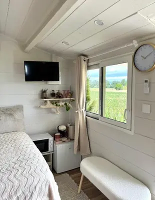 a bedroom with a bed and a window and a clock at La paillote , confort toutes saisons in Moussan