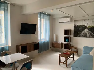 a living room with a blue couch and a tv at Nusa in Narbonne