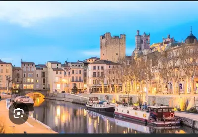 a river with boats in a city with a castle at Nusa in Narbonne