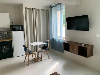 a room with a table and two chairs and a television at Nusa in Narbonne