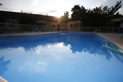 a swimming pool with blue water in front of a house at Rocade capsule bungalow in Pamiers
