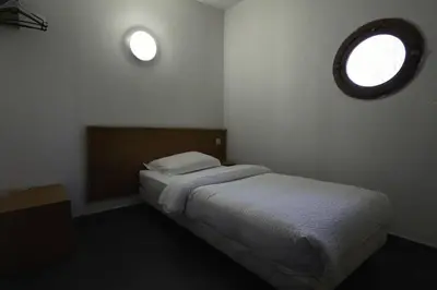 a small bedroom with a bed and a window at Rocade capsule bungalow in Pamiers