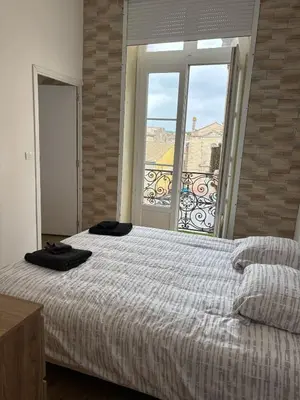 a bedroom with a bed and a large window at Appartement Moderne au centre de NARBONNE in Narbonne