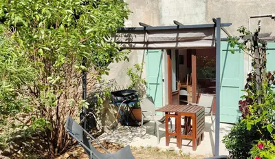 a patio with a table and chairs and an umbrella at Gite du domaine de Couchalou in Fontjoncouse