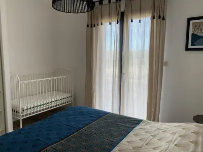 a bedroom with a crib in front of a window at Villa neuve calme - piscine privée - vue sur les vignes in Roquecourbe-Minervois
