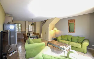 a living room with green furniture and a kitchen at 2 Bedroom Gorgeous Home In St-Laurent-De-La-Cabr in Saint-Laurent-de-la-Cabrerisse