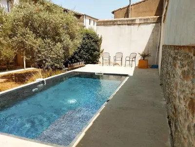 a swimming pool in a backyard with chairs around it at Very Chic Townhouse with Pool and Garage in Carcassonne