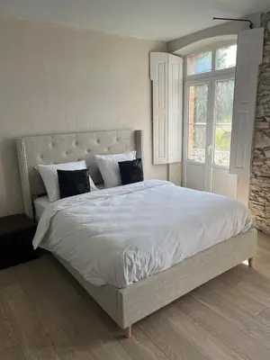 a large white bed in a bedroom with a window at Domaine du BaRon in Alzonne