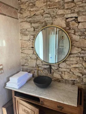 a bathroom sink with a mirror on a stone wall at Domaine du BaRon in Alzonne