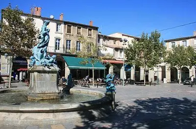 a fountain in the middle of a street with buildings at Domaine du BaRon in Alzonne