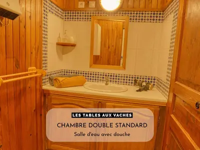 a bathroom with a sink and a sign on the door at Les Tables Aux Vaches à la Salvetat in La Salvetat
