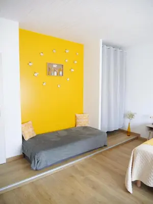 a bedroom with a bed with a yellow wall at Les Tables Aux Vaches à la Salvetat in La Salvetat