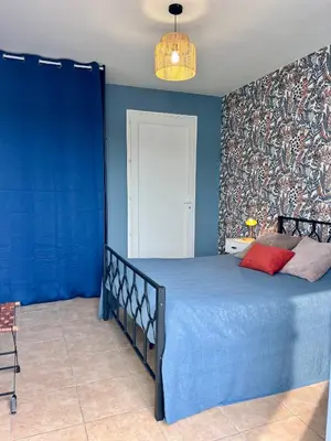 a blue bedroom with a bed and a blue wall at Suite Bleuet in Peyriac-de-Mer