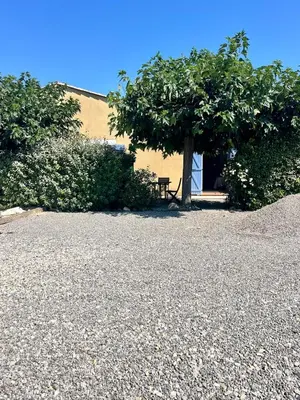 a picnic table under a tree next to a building at Suite Bleuet in Peyriac-de-Mer