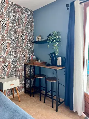 a table and stools in a room with a blue wall at Suite Bleuet in Peyriac-de-Mer