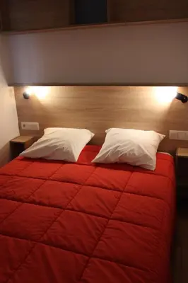 a bedroom with a red bed with two pillows at Oasis bora bora 4 personnes in Pamiers