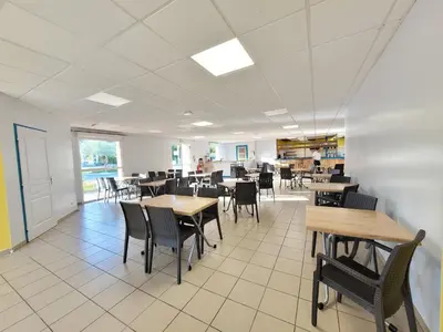 a dining room with tables and chairs and a cafeteria at Oasis bora bora 4 personnes in Pamiers