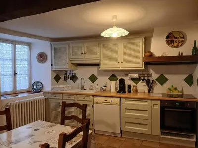 a kitchen with white cabinets and a table at Charmante maison de village in La Digne-dʼAmont