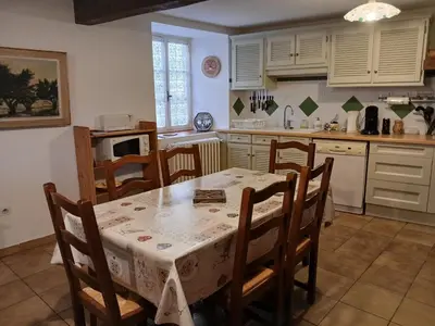 a kitchen with a table and chairs and a kitchen with white cabinets at Charmante maison de village in La Digne-dʼAmont