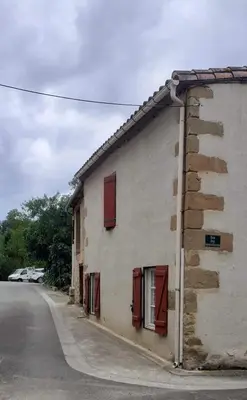 a building with red shuttered windows on a street at Charmante maison de village in La Digne-dʼAmont