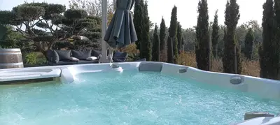 a hot tub in a yard with an umbrella at Logement entre mer et vignes in Fitou