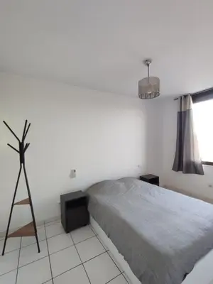 a white bedroom with a bed and a tripod at Logement entre mer et vignes in Fitou