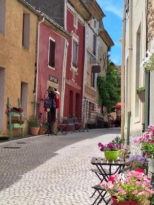 an empty street with flowers and tables and buildings at La Retraite in Assignan