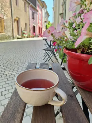 a cup of coffee sitting on a wooden table with flowers at La Retraite in Assignan
