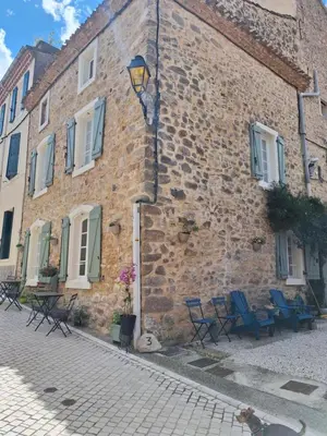 a brick building with blue chairs and a lamp at La Retraite in Assignan