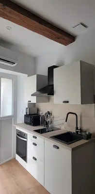 a kitchen with white cabinets and a stove top oven at Studio au cœur de Castelnaudary in Castelnaudary