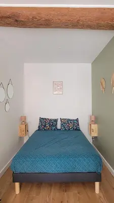 a bedroom with a bed with a blue comforter at Studio au cœur de Castelnaudary in Castelnaudary
