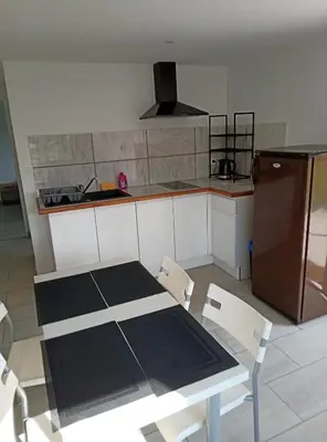 a kitchen with a table and chairs and a refrigerator at Havre de paix moderne aux portes du centre ville in La Celle-sous-Gouzon
