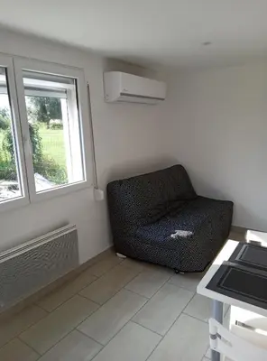 a living room with a chair and two windows at Havre de paix moderne aux portes du centre ville in La Celle-sous-Gouzon
