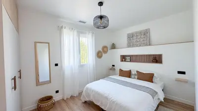 a white bedroom with a bed and a mirror at Maison Climatisée 5min Cité Terrasse et Parking AK in Carcassonne