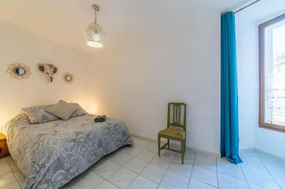 a bedroom with a bed and a chair and a window at Elegant 2 bedrooms flat - 8mn walk from trainstation in Narbonne
