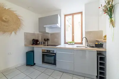 a kitchen with white cabinets and a sink and a window at Elegant 2 bedrooms flat - 8mn walk from trainstation in Narbonne