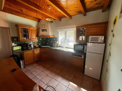 a kitchen with wooden cabinets and a white refrigerator at Jolie maison avec piscine in Sigean